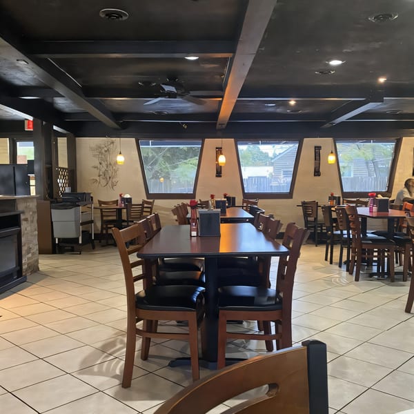 Interior of Christopher's Steakhouse and Seafood, featuring dark tables, wooden chairs, and large windows.