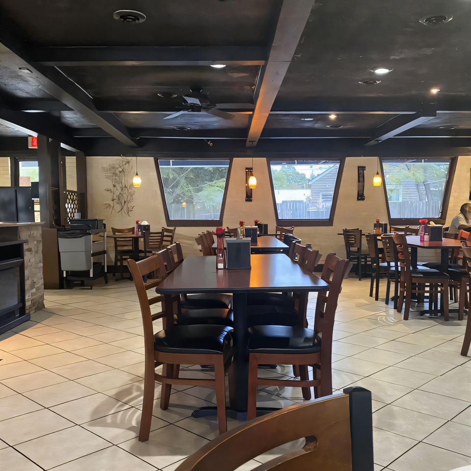 Interior of Christopher's Steakhouse and Seafood, featuring dark tables, wooden chairs, and large windows.